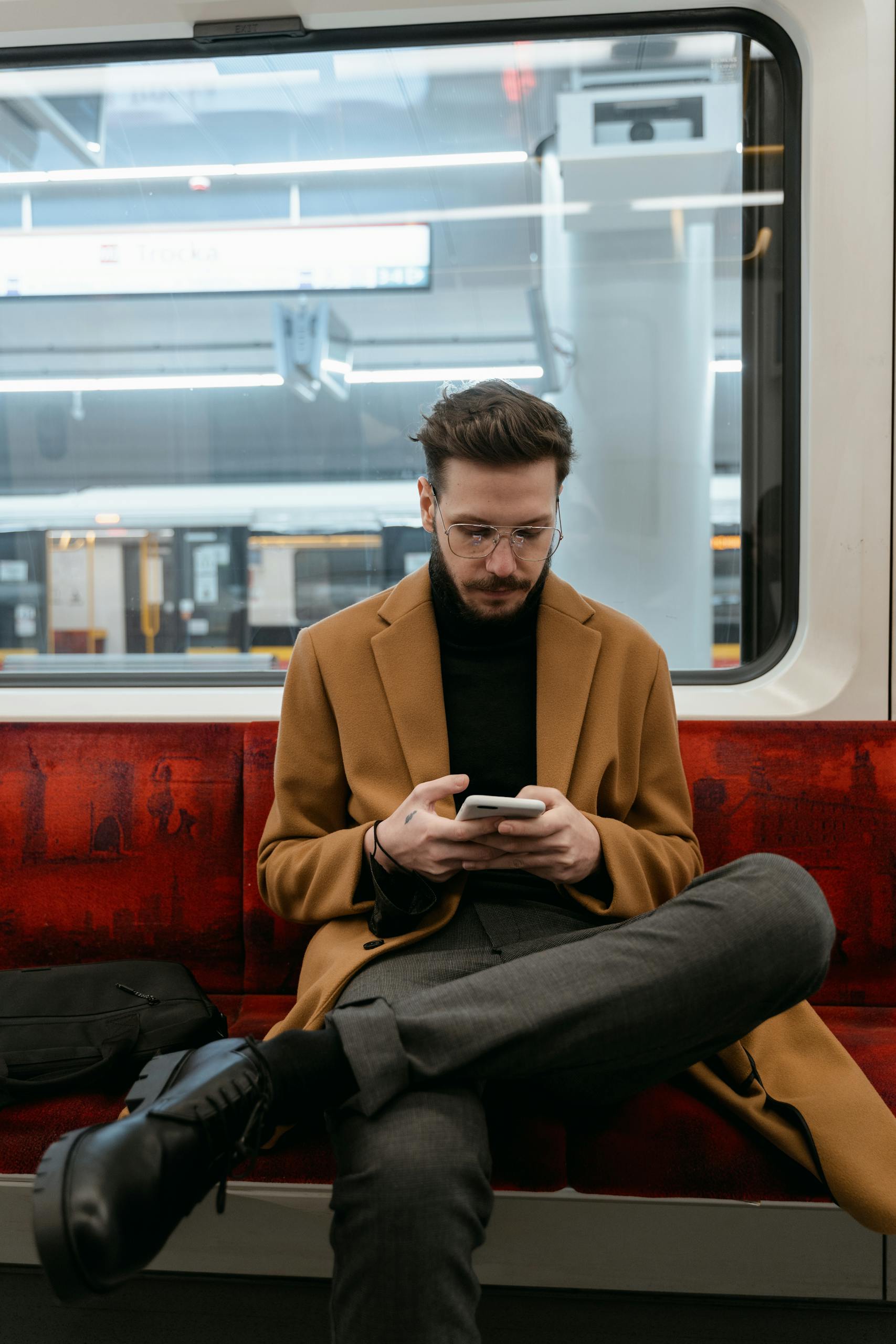 Caucasian man texting on smartphone while commuting by subway train.